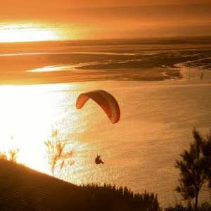 Faire du parapente devant le coucher de soleil au dessus de la dune du Pilat